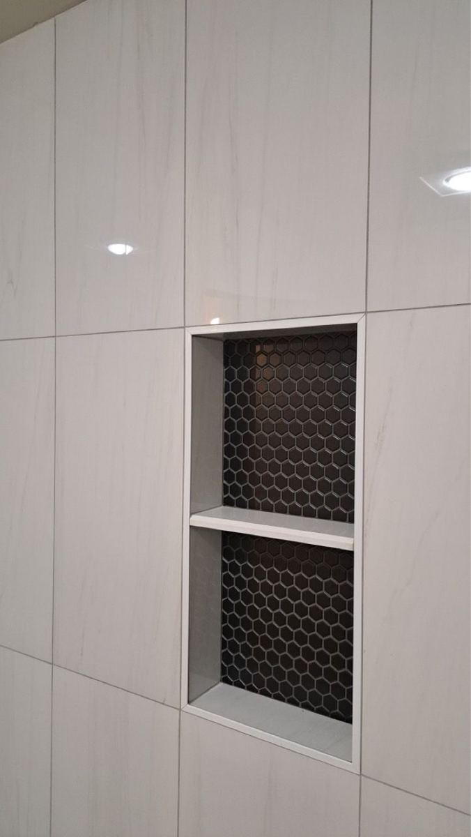 Shower niche with black hexagon mosaic tile