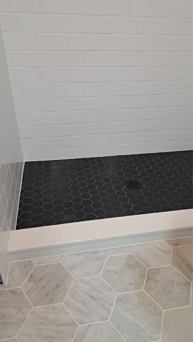 Shower floor with black mosaic tile and hexagon floor tile