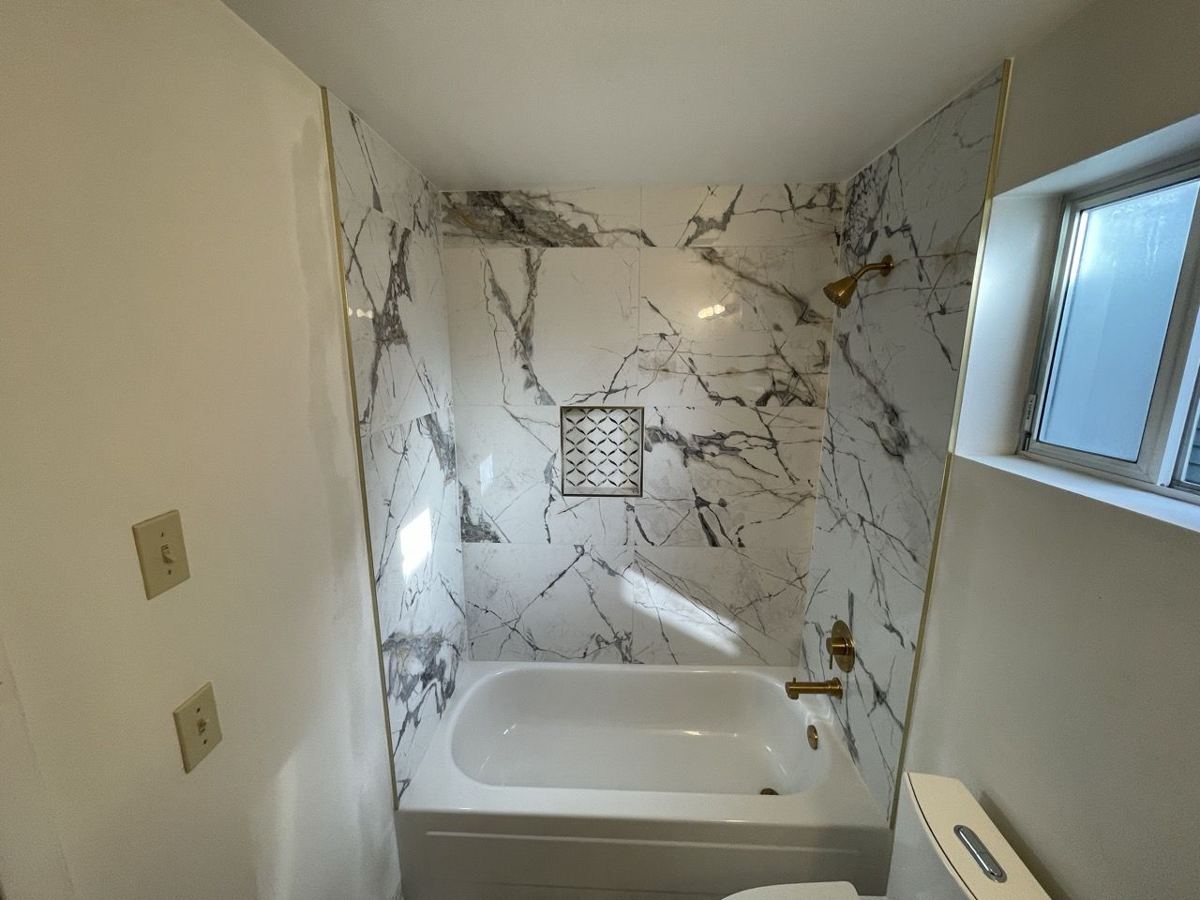 Tub with marble-look tile and mosaic niche
