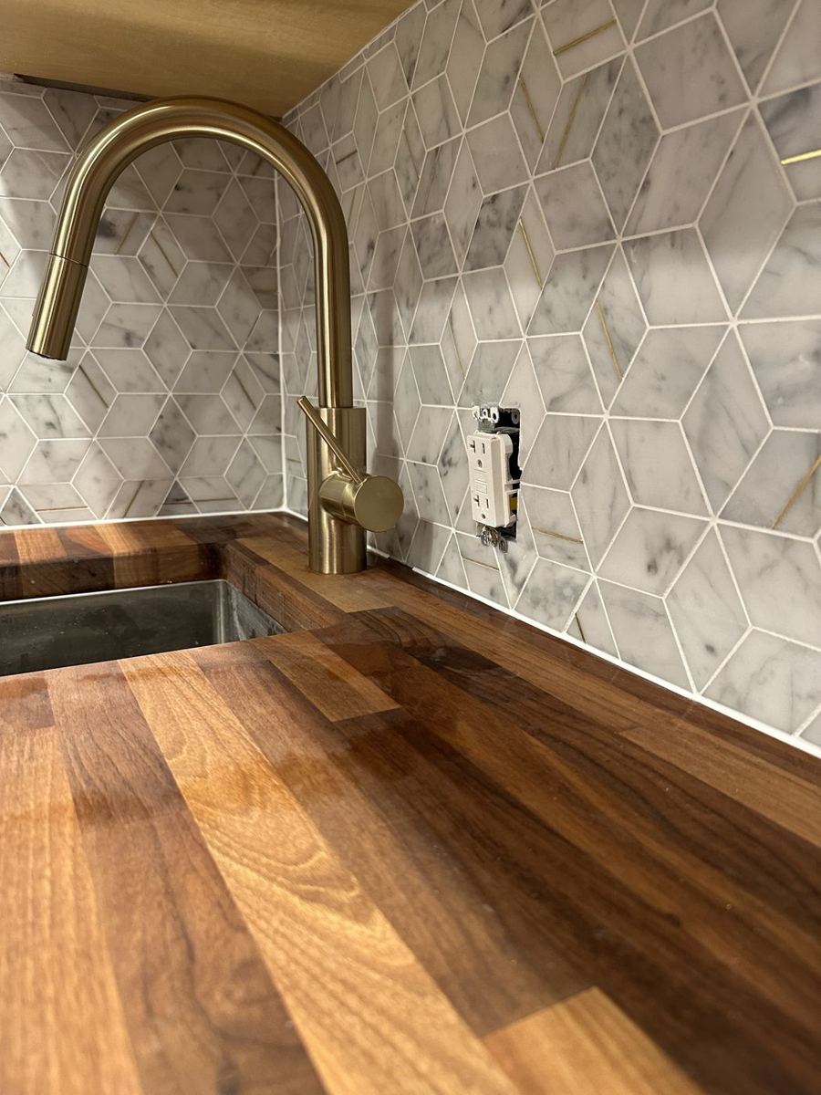 Hexagon marble backsplash behind a gold faucet