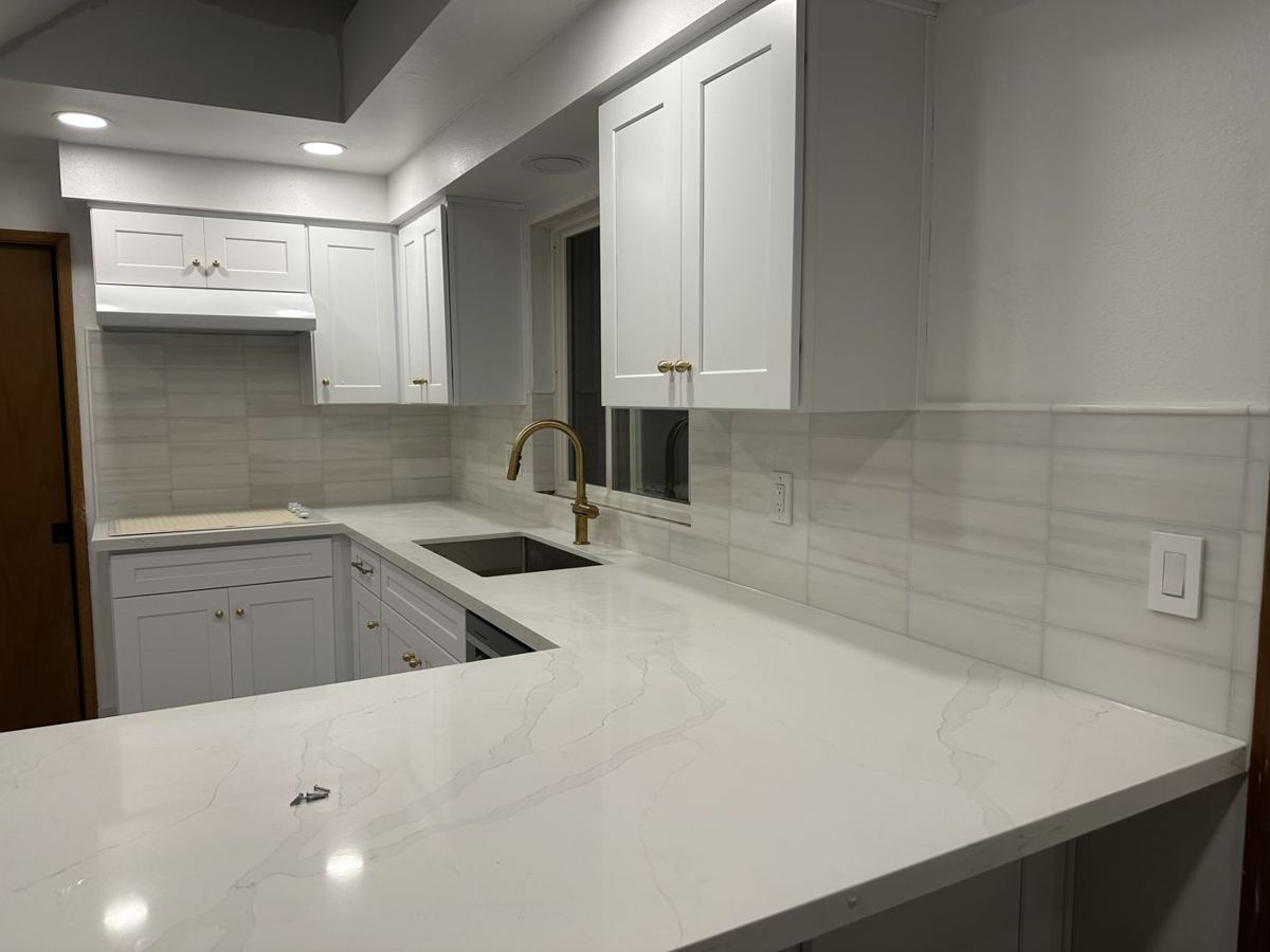White cabinets with quartz counters and a tile backsplash